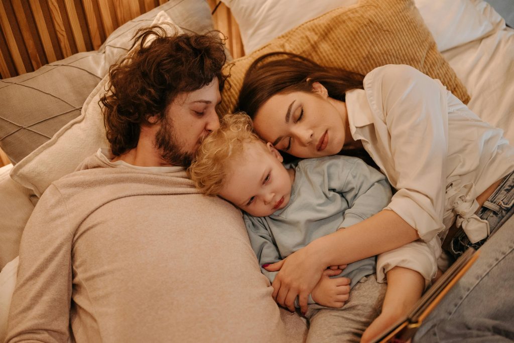 A loving family of three enjoying a relaxing moment in bed together, embracing warmth and affection.