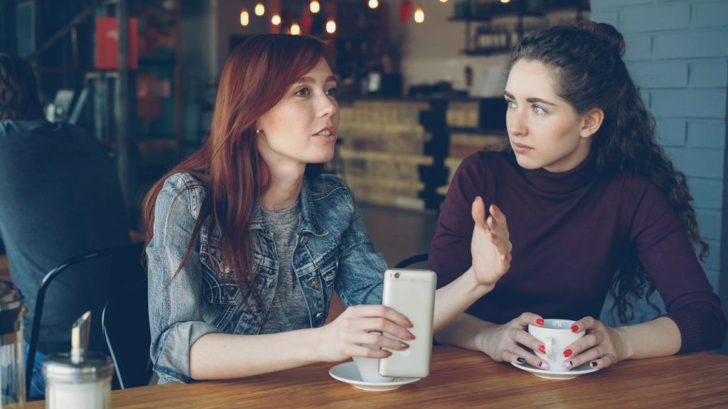 Two young women having a conversation over coffee in a cozy café.