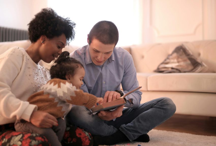 A diverse family enjoying storytime together, fostering love and learning indoors.